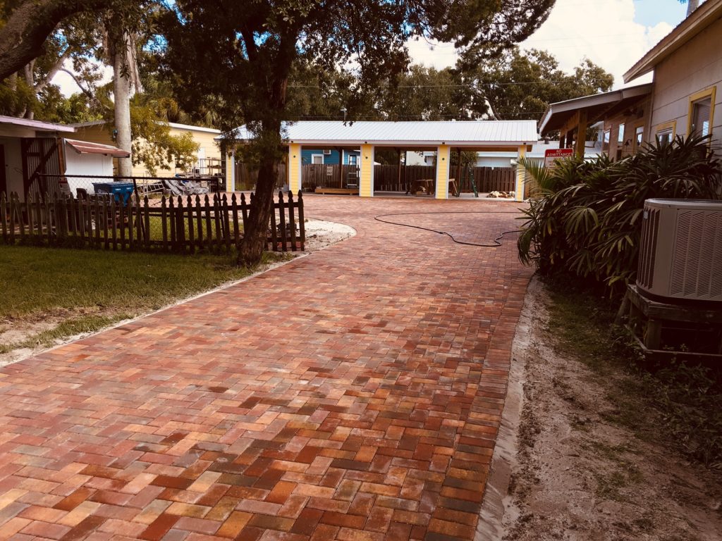 Long driveways covered with brick paversand surrounded by a garden