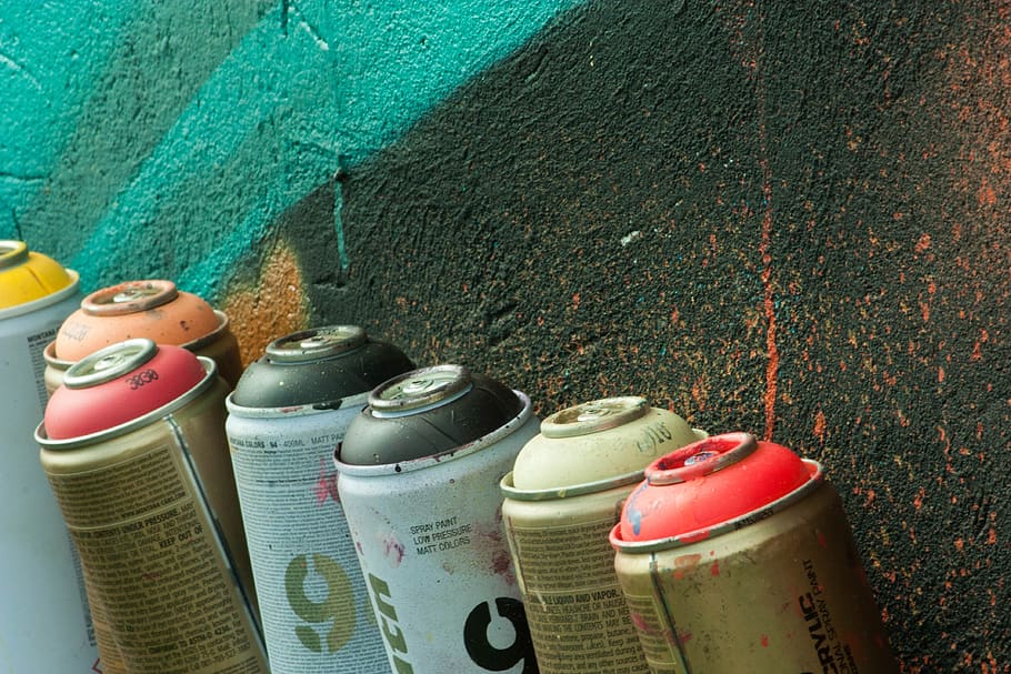 Cans of pray paint next to a painted wall